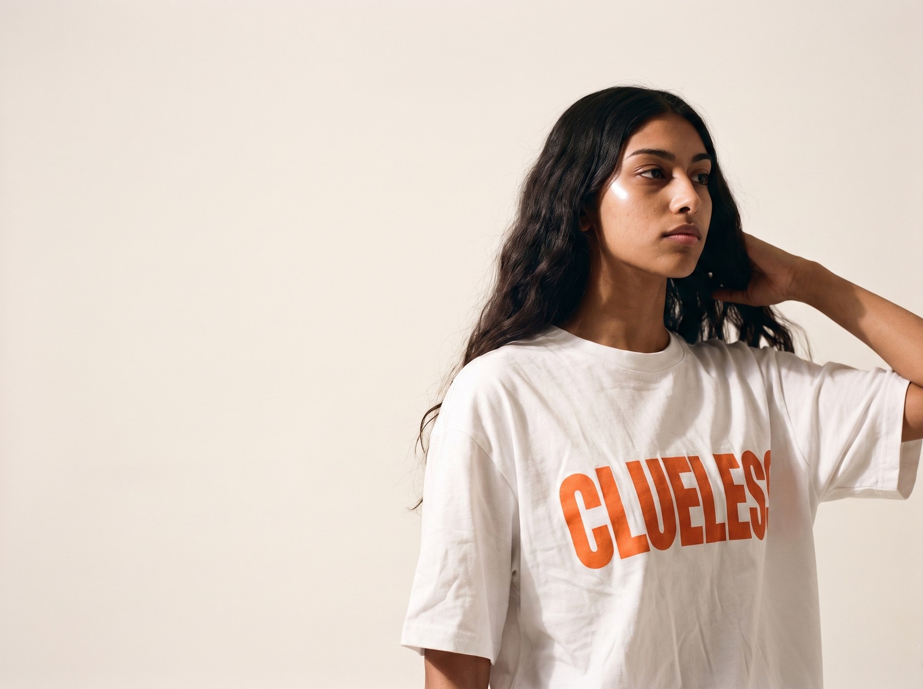Model wearing the white Clueless oversized tee with the orange chest print